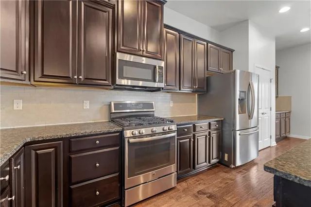 a kitchen with granite countertop a refrigerator stove and cabinets