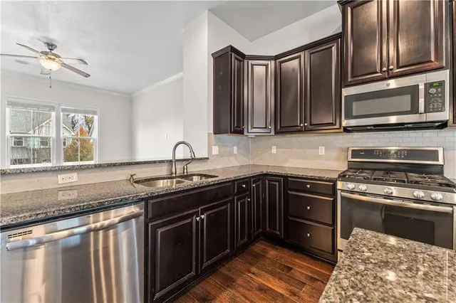 a kitchen with granite countertop a sink and stainless steel appliances