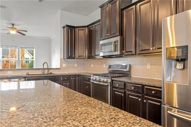 a kitchen with stainless steel appliances granite countertop a stove a sink and a microwave