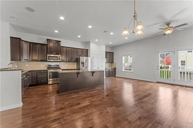 a large kitchen with stainless steel appliances granite countertop a large counter top a stove a sink and a refrigerator