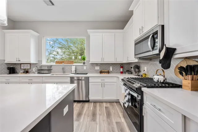 a kitchen with stainless steel appliances granite countertop white cabinets granite counter tops and a window