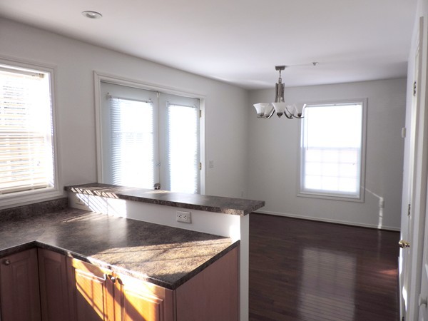 32 Junction Street, Unit 5 Needham, MA 02492 - Photo 3 of 4 a view of a kitchen island a sink dishwasher and wooden floor
