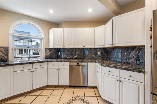 a kitchen with granite countertop white cabinets stainless steel appliances a sink and a window
