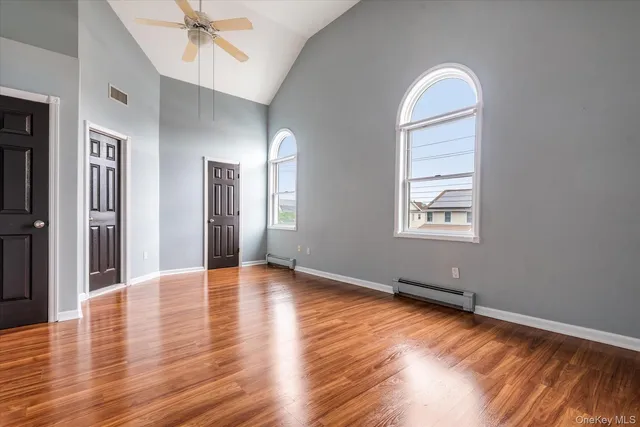 an empty room with wooden floor closet and windows