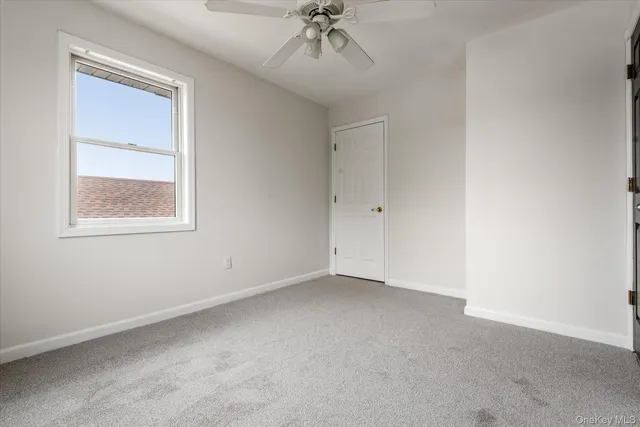 an empty room with a chandelier fan and windows
