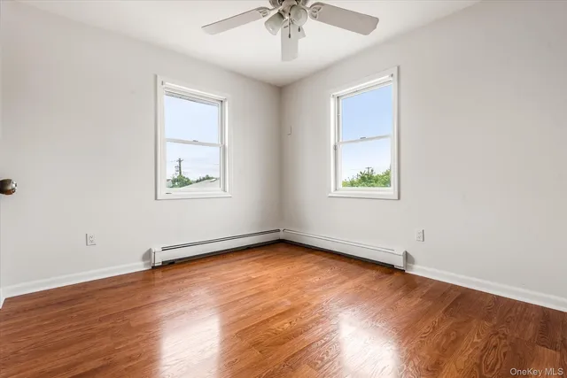 an empty room with wooden floor chandelier and windows