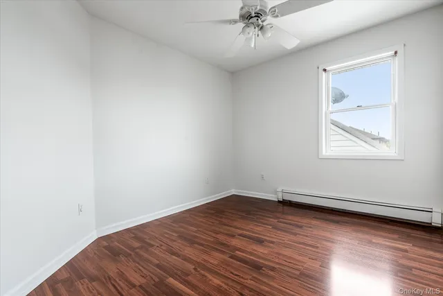 an empty room with wooden floor chandelier fan and windows
