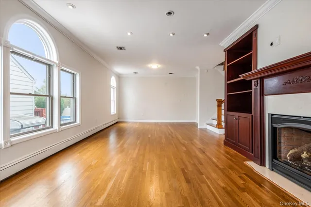 a view of an empty room with wooden floor fireplace and a window