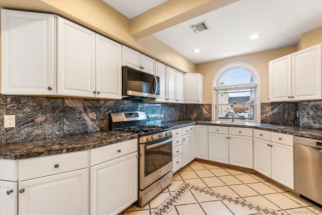 a kitchen with granite countertop a sink stainless steel appliances and white cabinets