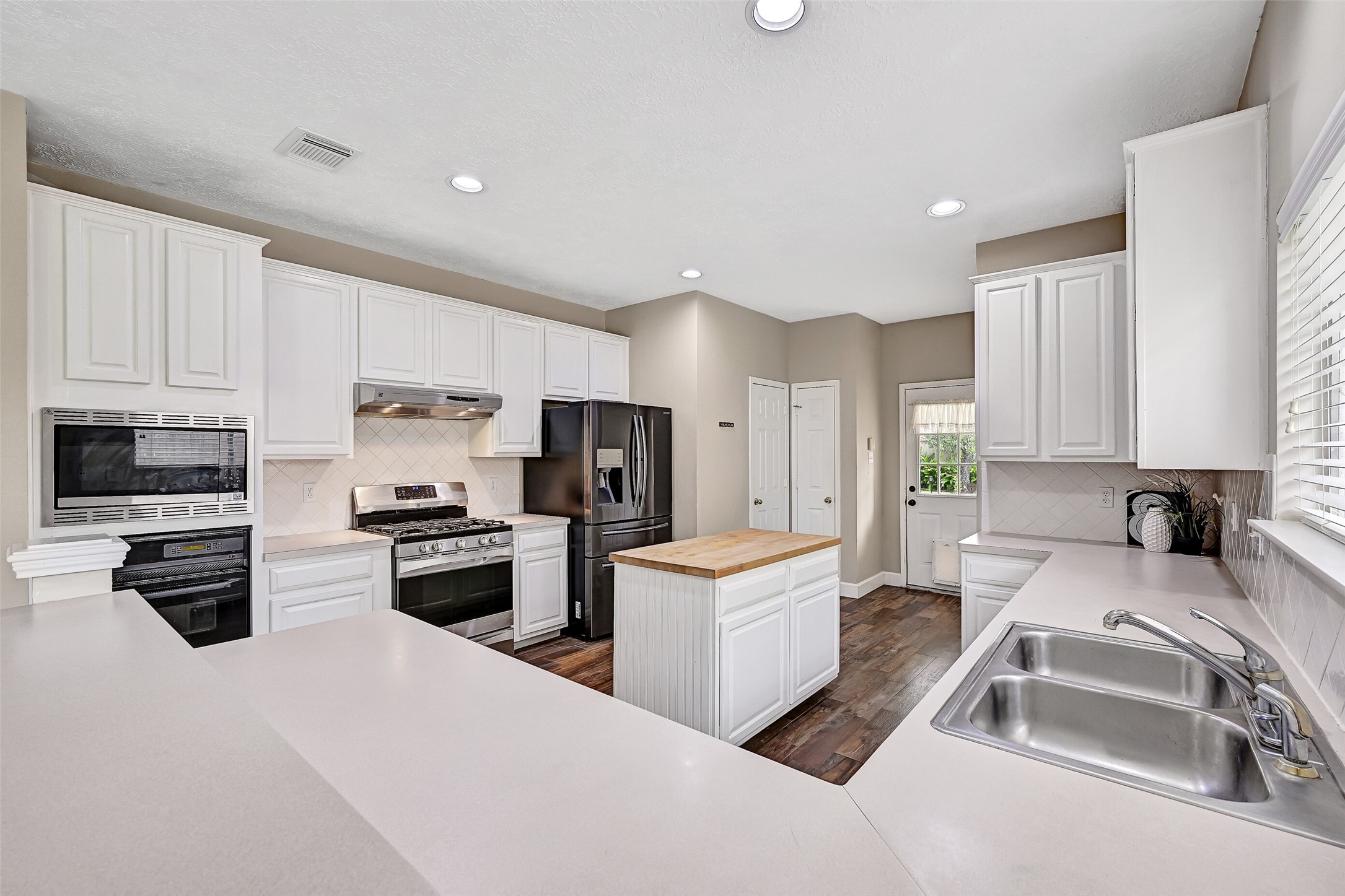 1606 Falcon Ridge Boulevard Friendswood, TX 77546 - Photo 12 of 24 a kitchen with stainless steel appliances a stove a sink a refrigerator a center island and cabinets