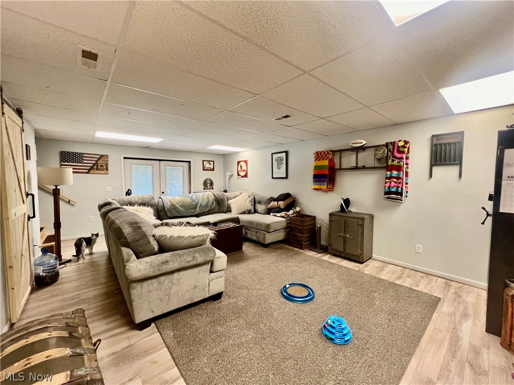 39589 National Road Bethesda, OH 43719 - Photo 27 of 35 Living room with a barn door, light hardwood / wood-style floors, french doors, and a paneled ceiling