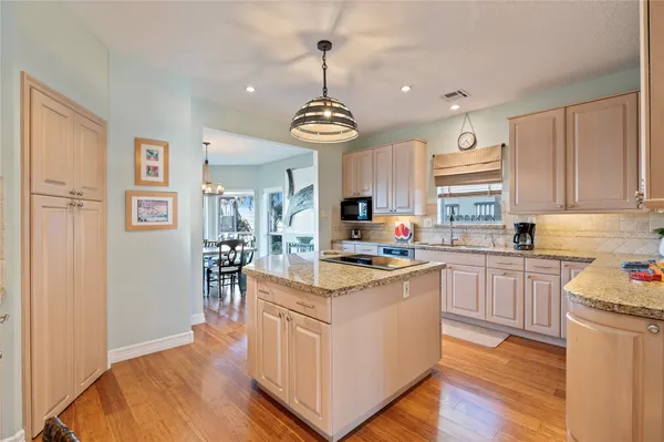 a open kitchen with stainless steel appliances granite countertop a stove top oven a refrigerator a sink dishwasher and a dining table with wooden floor