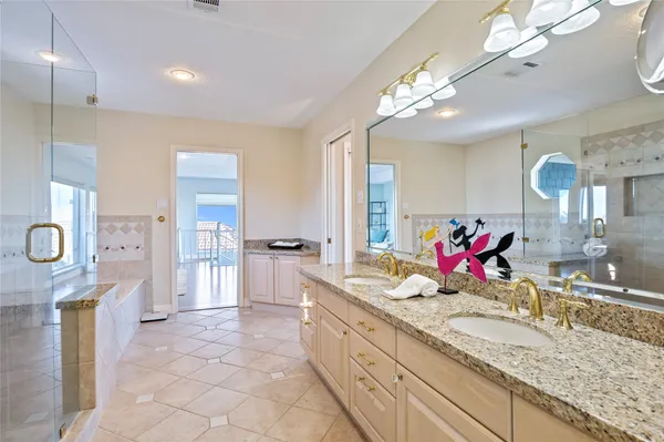 a bathroom with a granite countertop double vanity sink a mirror and a shower