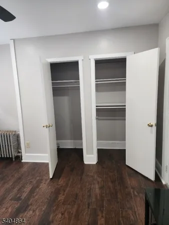 a view of an empty room with wooden floor and closet