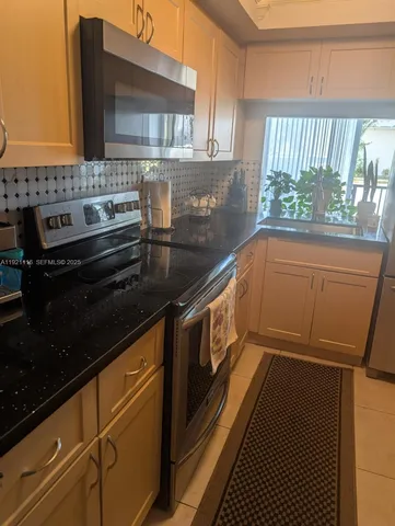 a kitchen with granite countertop a stove and a wooden cabinets