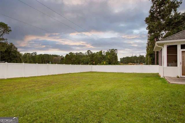 a view of white house with a big yard and large trees