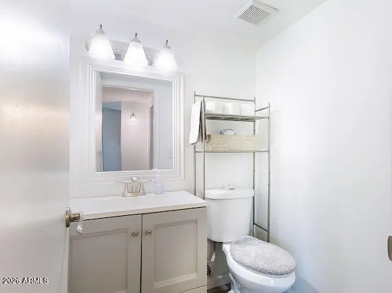 a bathroom with a toilet a sink a mirror and vanity