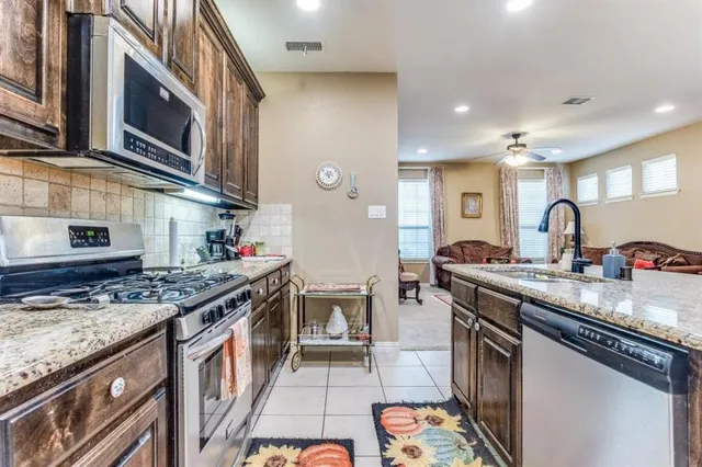 a kitchen with stainless steel appliances granite countertop a stove a sink and a microwave