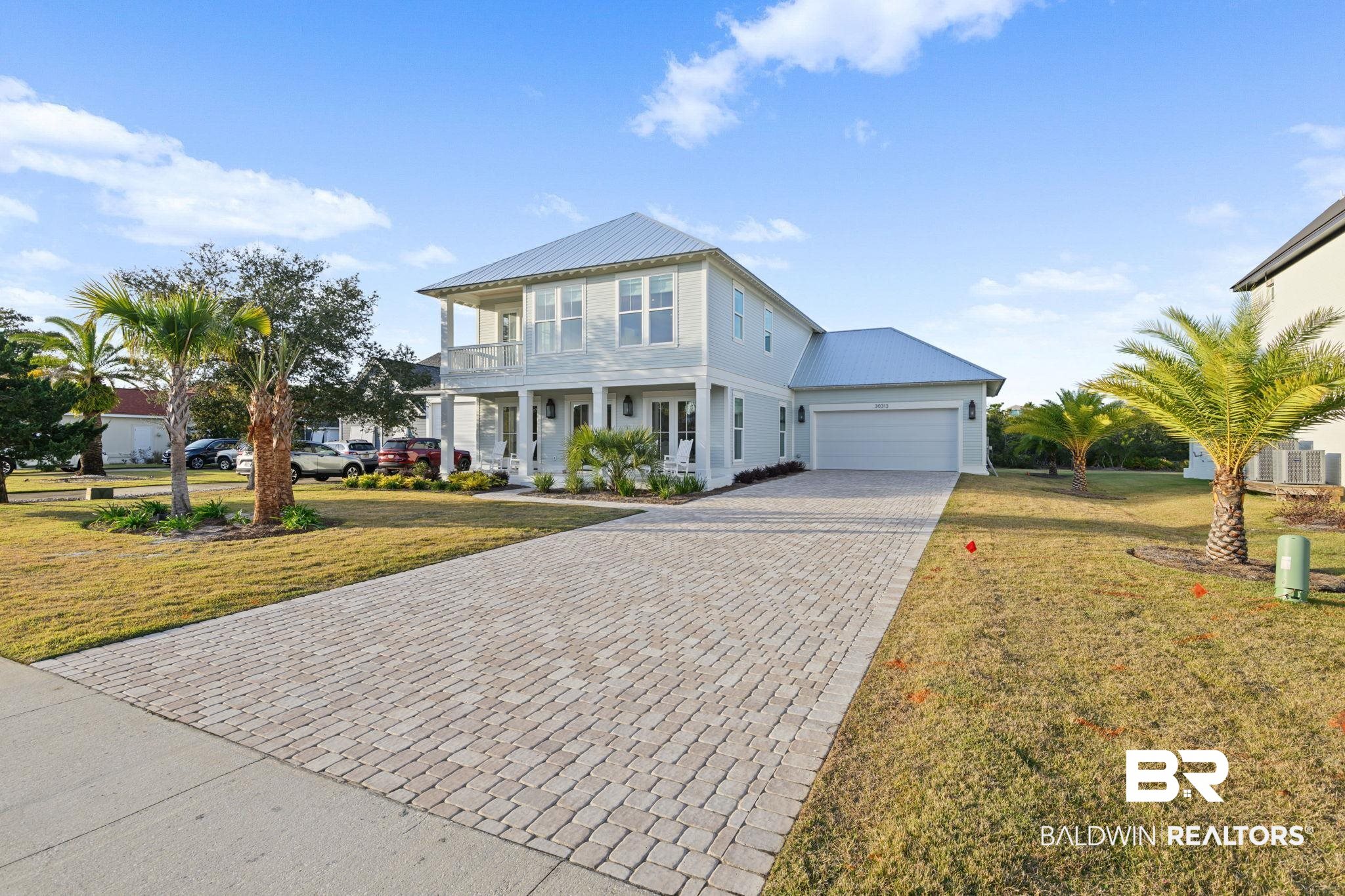 30313 River Road Orange Beach, AL 36561 - Photo 3 of 50 View of front of property with a front lawn, decorative driveway, a metal roof, and covered porch