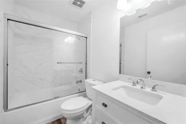a bathroom with a granite countertop sink toilet and shower