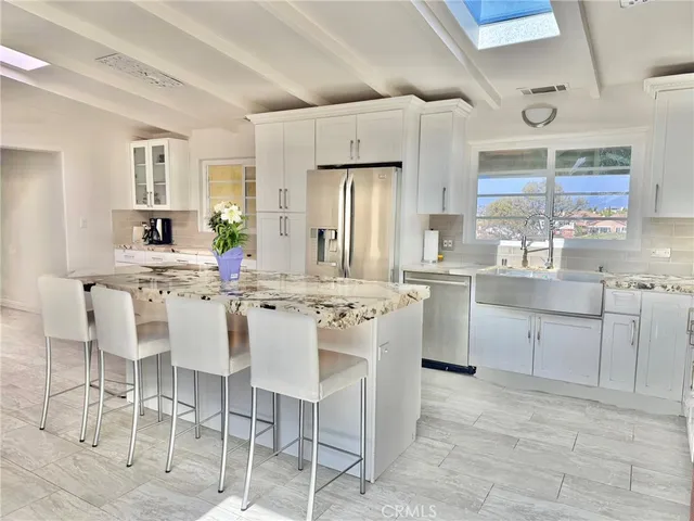 a kitchen with granite countertop a sink cabinets and stainless steel appliances