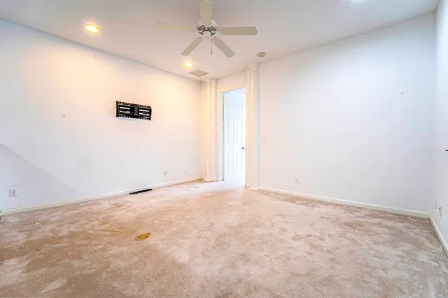 an empty room with a ceiling fan and window