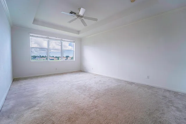 an empty room with windows and ceiling fan