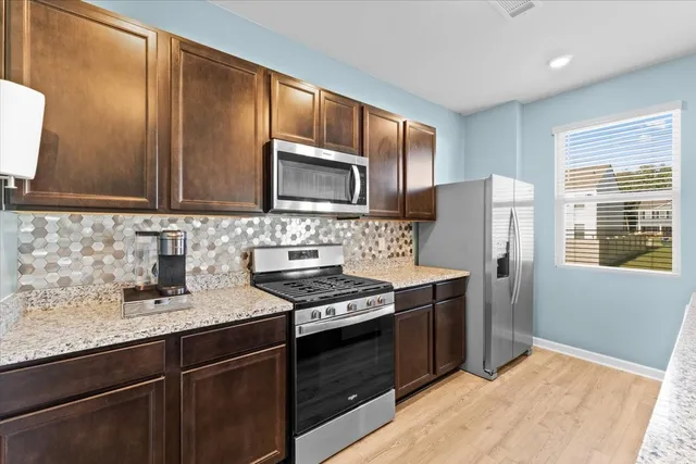a kitchen with stainless steel appliances granite countertop wooden cabinets stove top oven and sink