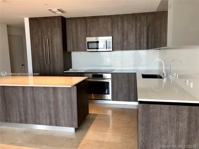 a kitchen with stainless steel appliances a refrigerator a sink a stove and a microwave