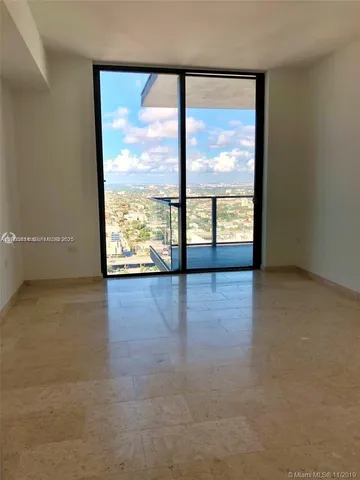 an empty room with wooden floor and windows with city view