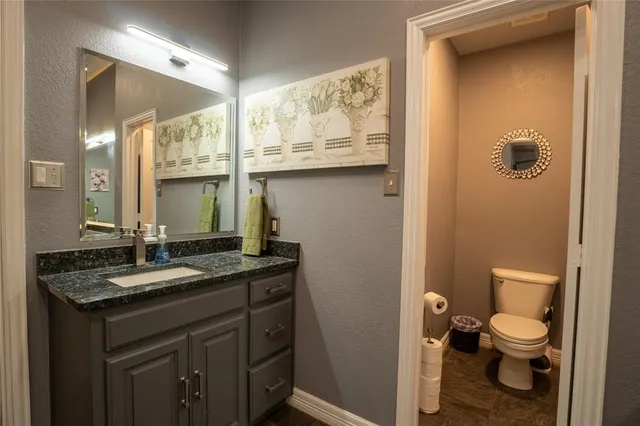 a bathroom with a granite countertop sink a toilet and a mirror