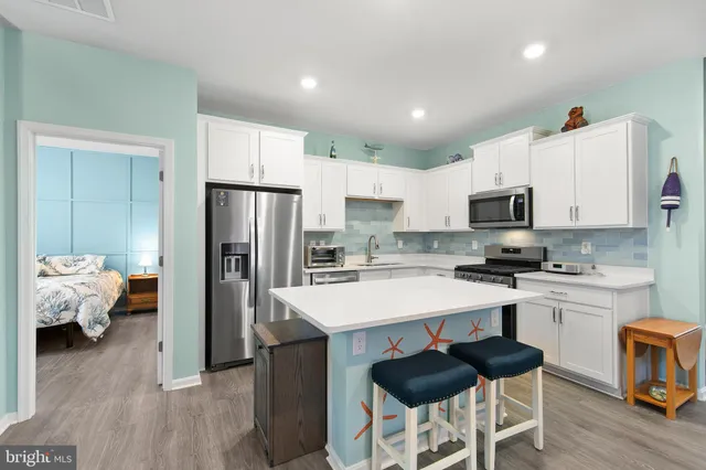 a kitchen with stainless steel appliances granite countertop a stove top oven a sink dishwasher and a refrigerator with wooden floor