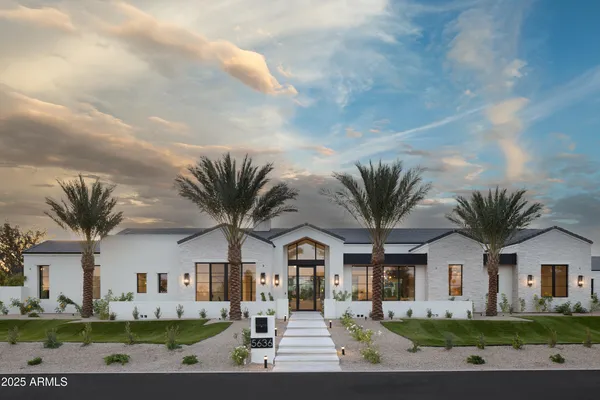 a view of a white house with a big yard and large trees
