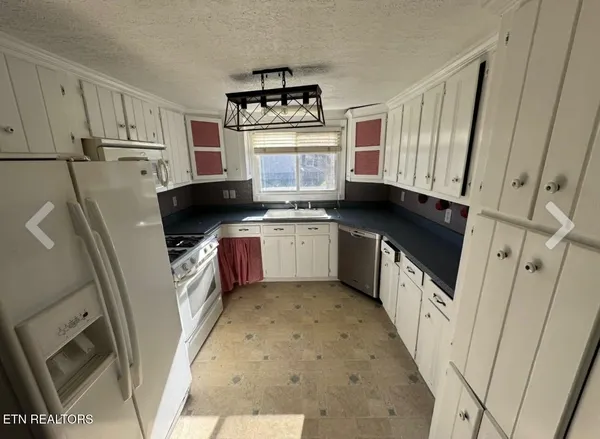 a kitchen with granite countertop a refrigerator a sink a stove a microwave and cabinets
