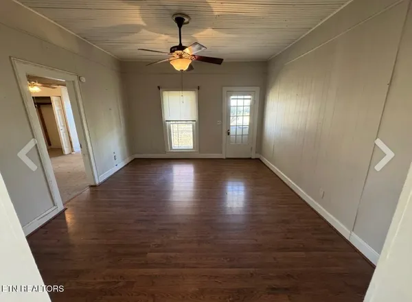a view of an empty room with wooden floor and a window