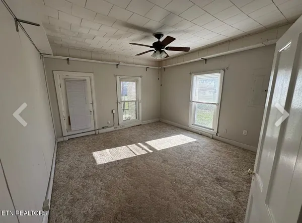 an empty room with windows and fan