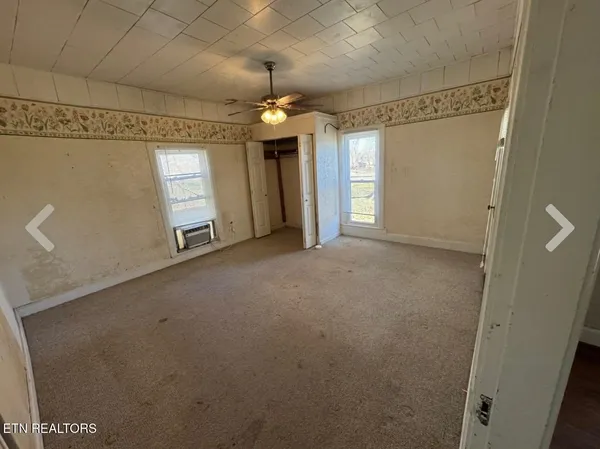 en empty room with windows and ceiling fan