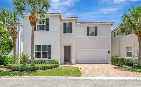 a view of a white house with a large windows and a large tree