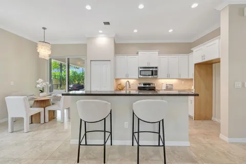 a kitchen with stainless steel appliances granite countertop a table chairs sink refrigerator and microwave