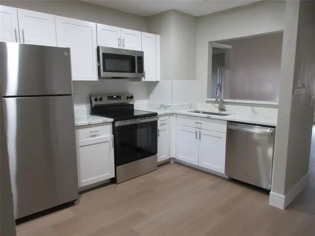 a kitchen with cabinets stainless steel appliances and a sink