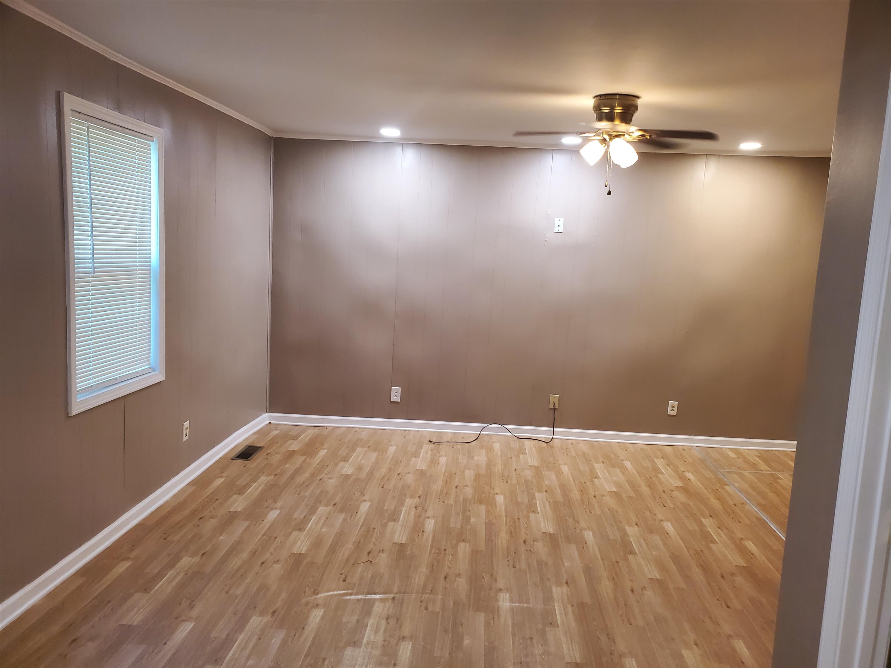 150 Dry Creek Road Toone, TN 38381 - Photo 2 of 6 an empty room with wooden floor chandelier fan and windows