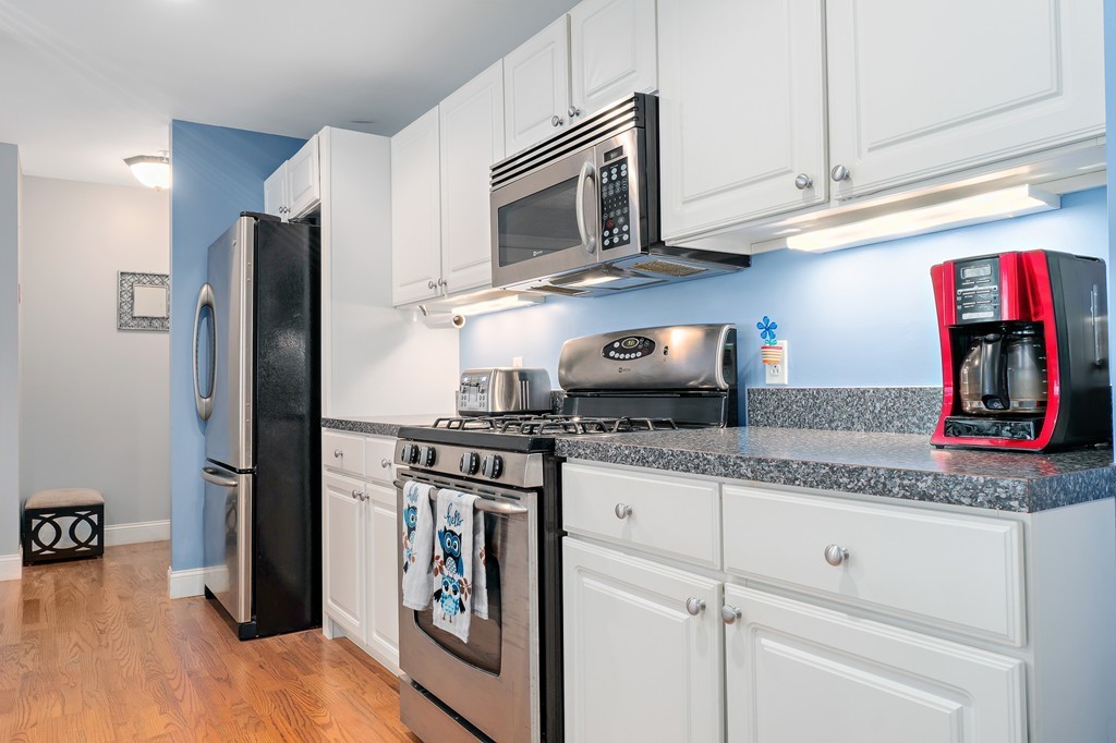 19 Broad Street, Unit 203 Merrimac, MA 01860 - Photo 7 of 20 a kitchen with granite countertop cabinets stainless steel appliances and wooden floor