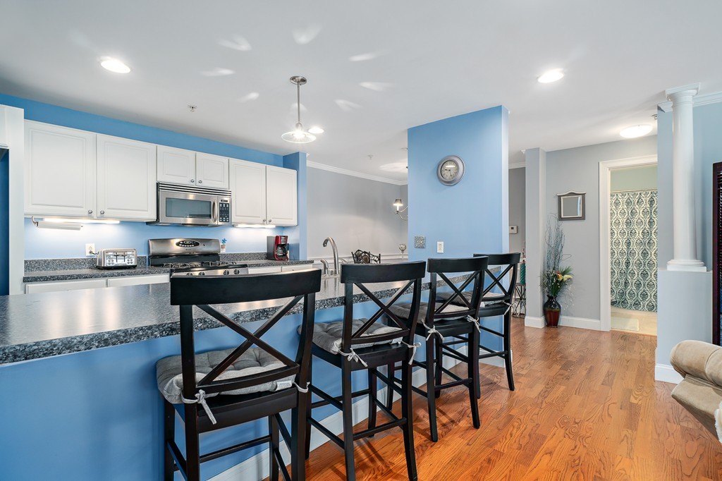 19 Broad Street, Unit 203 Merrimac, MA 01860 - Photo 9 of 20 a kitchen with stainless steel appliances kitchen island granite countertop a dining table chairs and granite counter tops