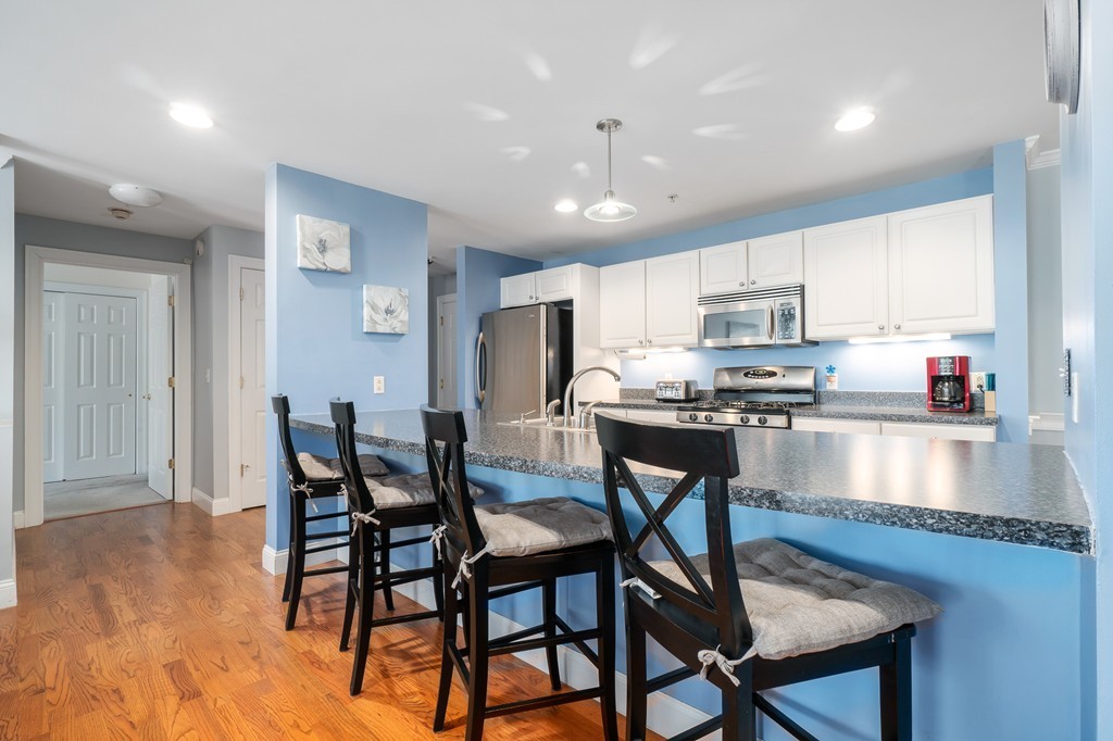19 Broad Street, Unit 203 Merrimac, MA 01860 - Photo 10 of 20 a kitchen with stainless steel appliances granite countertop a stove a refrigerator a kitchen island with a dining table and chairs