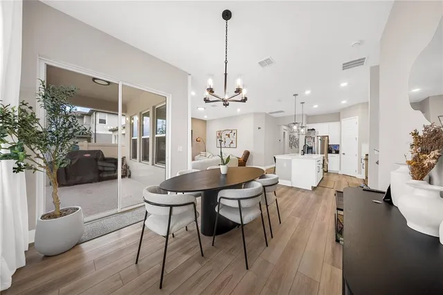 a view of a dining room and livingroom with furniture wooden floor a chandelier