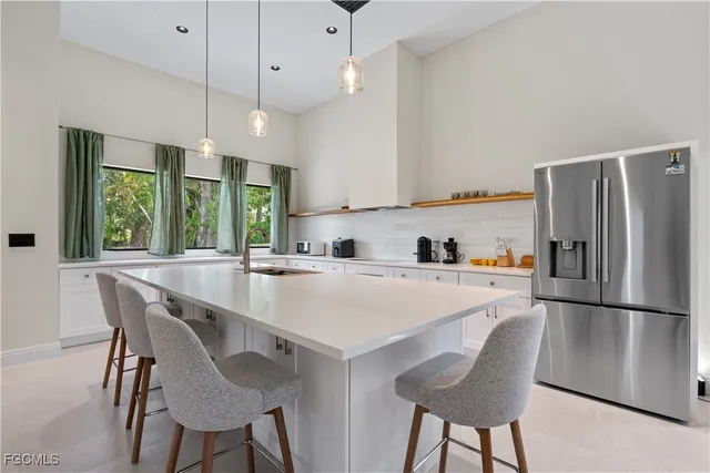 a kitchen with stainless steel appliances granite countertop a sink a stove a refrigerator and island with wooden floor