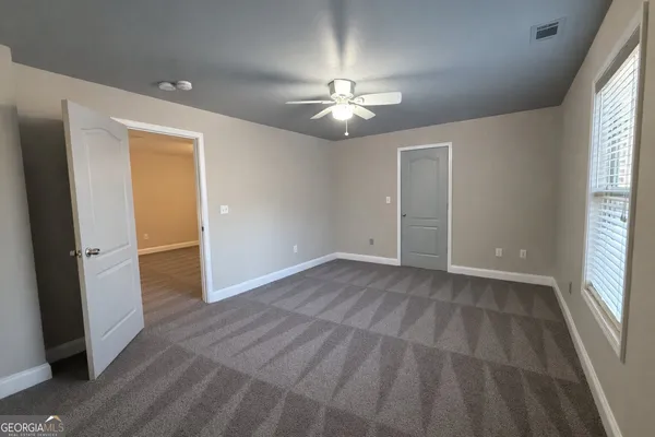 an empty room with windows and fan