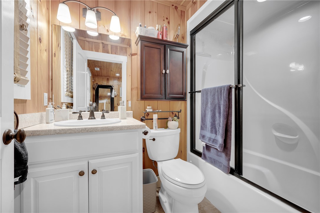 498 Raines Road Mountain Rest, SC 29664 - Photo 34 of 48 Warm wood-paneled walls pair with a modern white vanity and glass-enclosed shower.