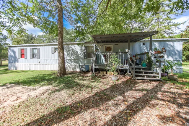 a view of a house that has a small yard and a large tree