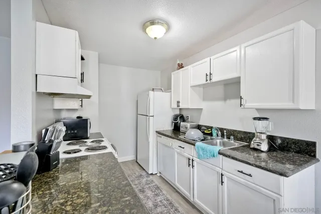 a kitchen with granite countertop a sink a stove and refrigerator